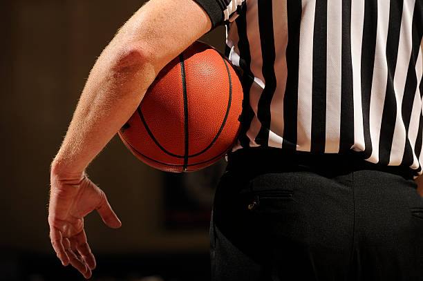 A Referee Holds A Basketball Under His Arm During A Timeout.